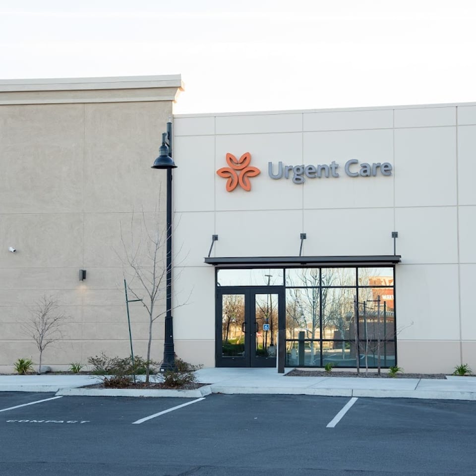 Exterior view of an Urgent Care building with a parking lot in the foreground.